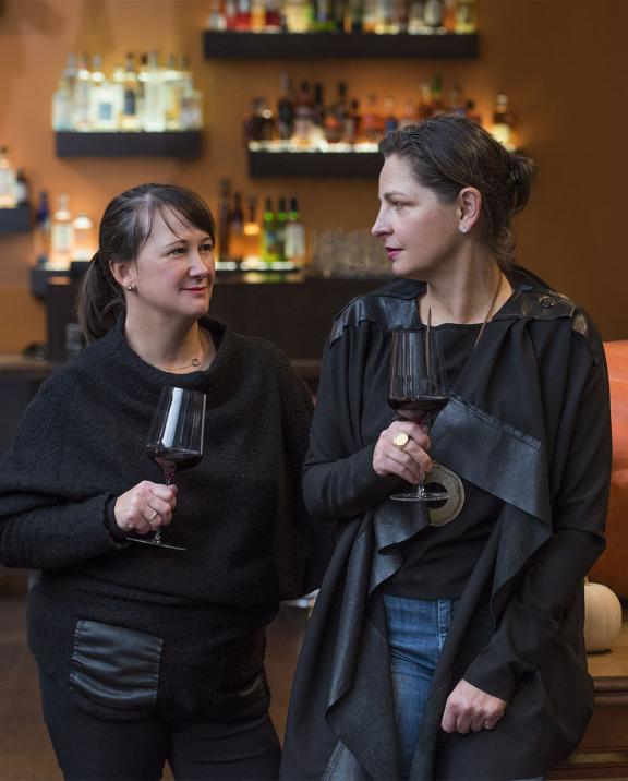 Ladies holding red wine while socializing at bar in Boston