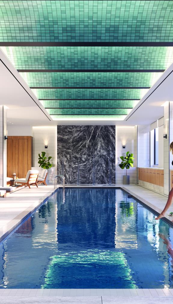 Woman dipping her toes in the water of indoor pool at the Quinn
