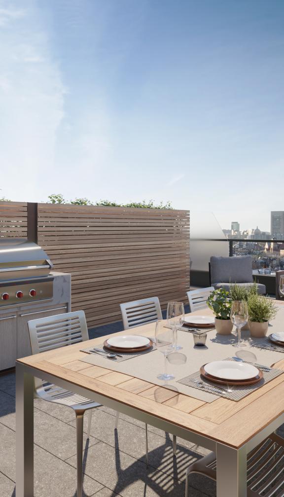 Sunny day on a rooftop patio with views of the Boston skyline at the Quinn